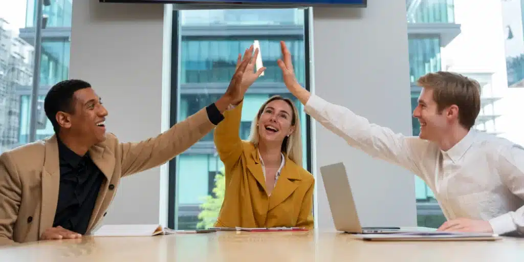 empreendedores sentados em uma mesa comemorando que conseguiram aumentar as vendas telecom