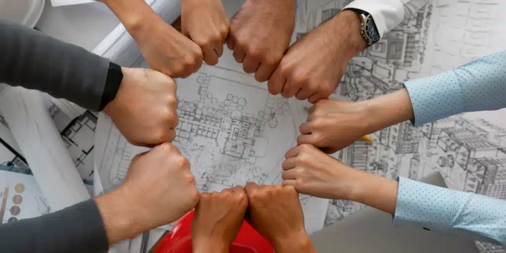 colaboradores de uma empresa com as mãos unidas em prol de um objetivo único. Isso garante que o clima organizacional da empresa está em bons níveis, porque demonstra a união da equipe e a satisfação do time