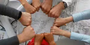 colaboradores de uma empresa com as mãos unidas em prol de um objetivo único. Isso garante que o clima organizacional da empresa está em bons níveis, porque demonstra a união da equipe e a satisfação do time