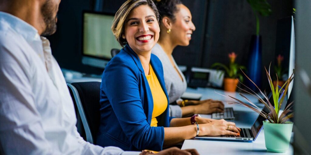 mulher sentada em frente ao computador sorrindo