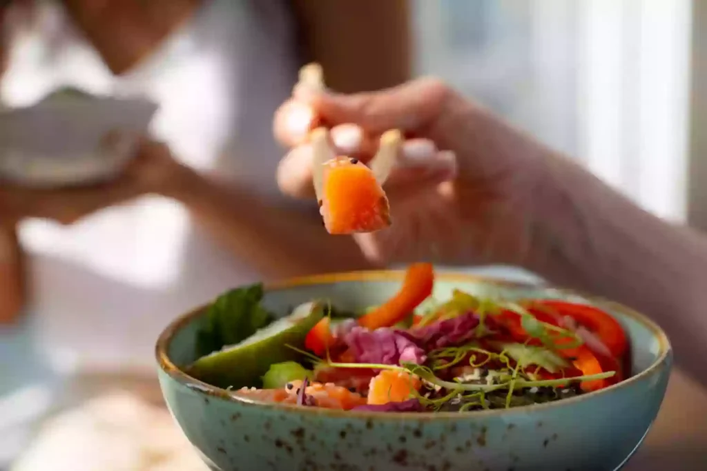 Pessoa comendo vegetais de uma tigela com alimentos funcionais
