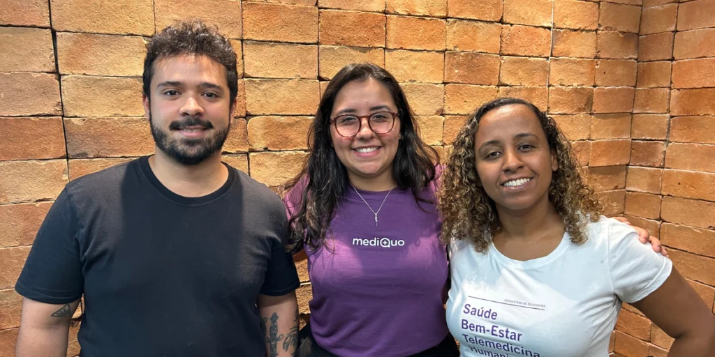 tres pessoas sorrindo parede de tijolos