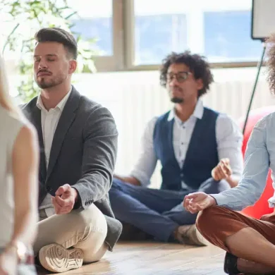colaboradores sentados no chão fazendo um exercício de meditação em uma empresa que se preocupa com a saúde mental das pessoas, colocando em prática e seguindo a NR-01