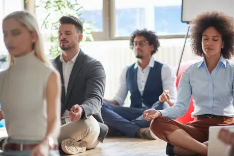 colaboradores sentados no chão fazendo um exercício de meditação em uma empresa que se preocupa com a saúde mental das pessoas, colocando em prática e seguindo a NR-01